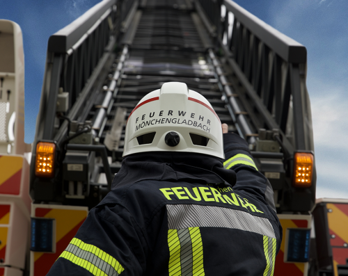 Feuerwehrmann steht vor einem Leiterwagen