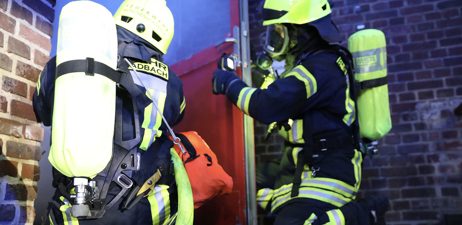 2 Feuerwehrmänner bereit sich auf das betreten eines brennenden Hauses vor