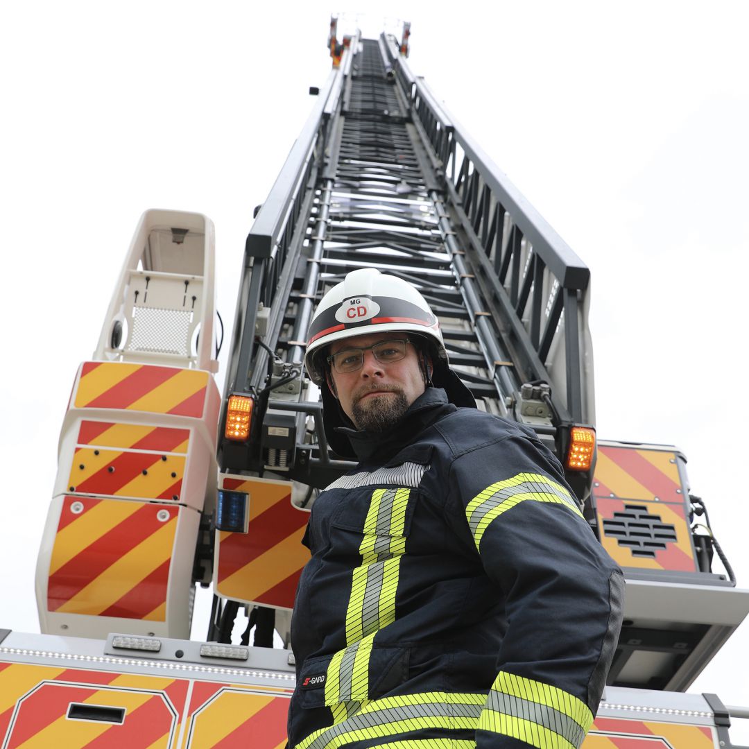 Feuerwehrmann steht vor einem Leiterwagen