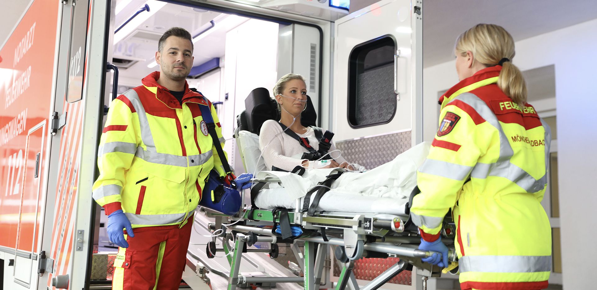 Notärzte der Feuerwehr-MG mit Patientin an Krankenwagen